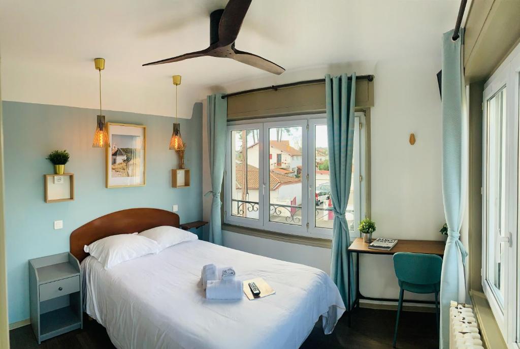 a bedroom with a bed with a ceiling fan and a window at Hotel Bistrot FINE in Anglet