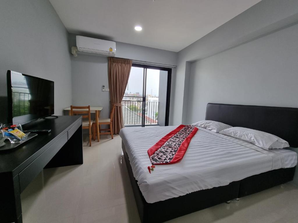 Dormitorio con cama, escritorio y TV en Tiara Place en Bangkok