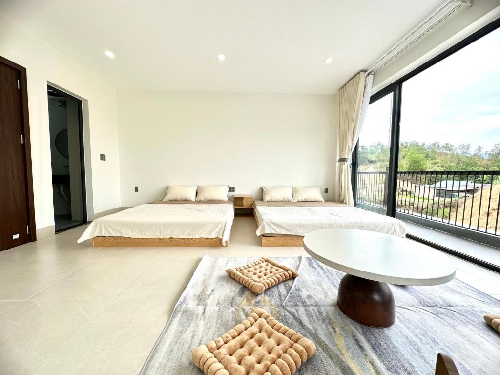1 Schlafzimmer mit 2 Betten, einem Tisch und einem großen Fenster in der Unterkunft Mỡ Villa Cao Bằng in Cao Bằng