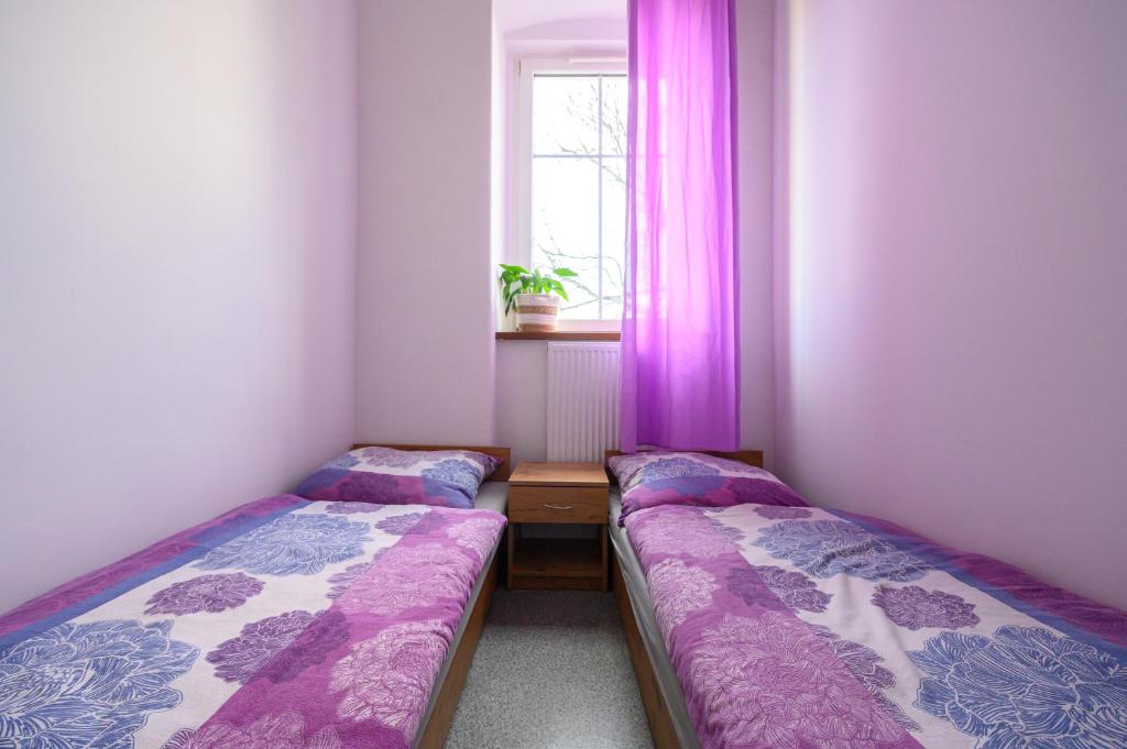 2 camas en una habitación pequeña con cortinas moradas en MRU Rooms, en Racibórz