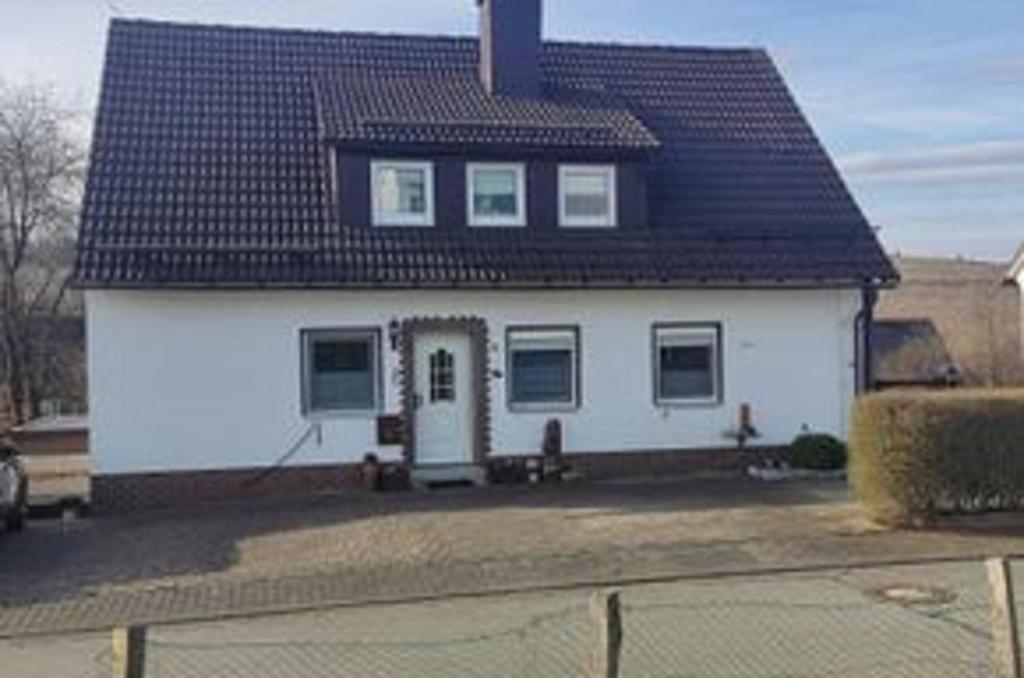 una casa bianca con tetto nero di Ferienwohnung Wanderlust a Bad Berleburg
