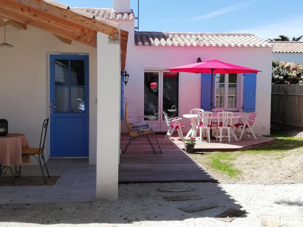 różowo-niebieski dom ze stołem i parasolem w obiekcie A moins de 500m de la plage vacances a L Epine w mieście LʼÉpine