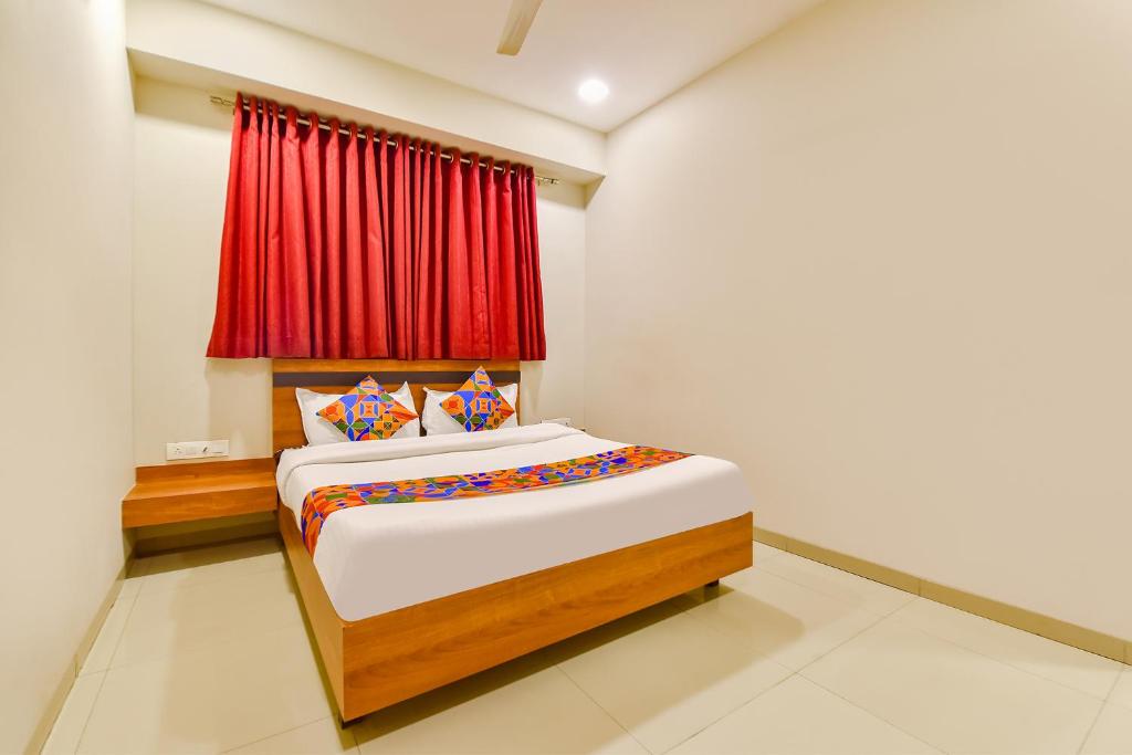 a bedroom with a bed with a red curtain at FabHotel Happinex in Surat