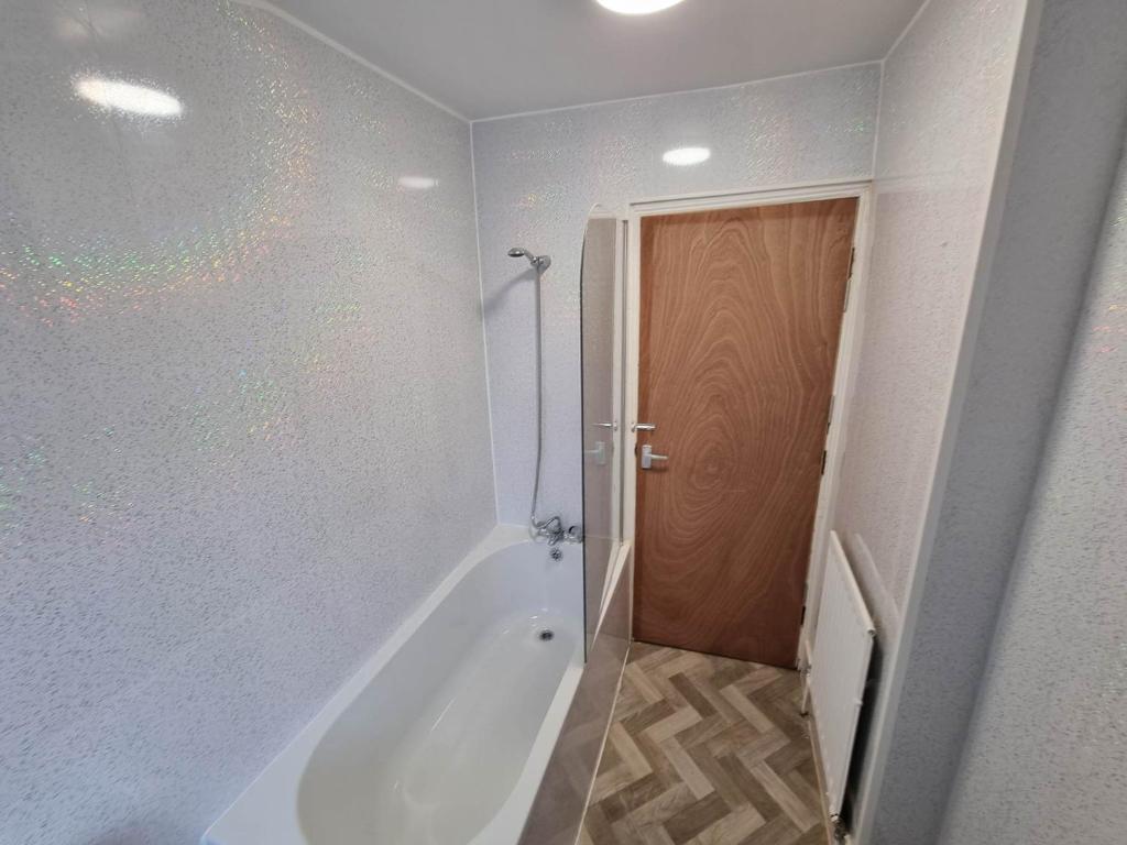 a bathroom with a tub and a shower and a door at 70 Southfield in Middlesbrough