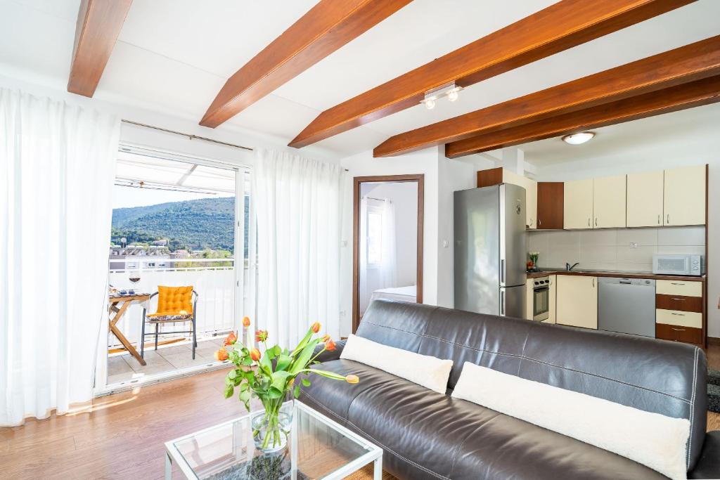a living room with a leather couch and a kitchen at Apartment Sunday in Mokošica