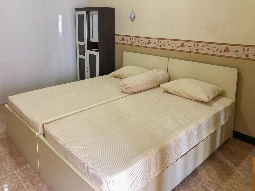 een bed met twee kussens in een kamer bij RedDoorz Syariah near Pasar Sleko Madiun in Madiun