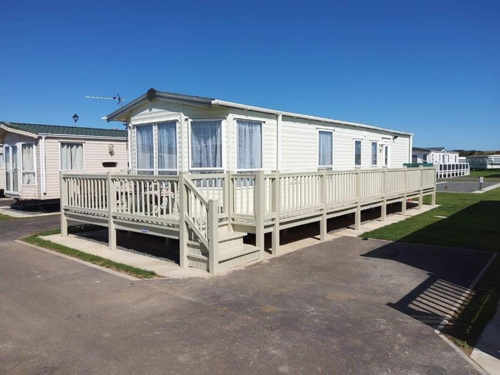 a white mobile home with a large deck at 6 BERTH DELUXE CARAVAN PG73 GOLDEN PALM in Chapel Saint Leonards