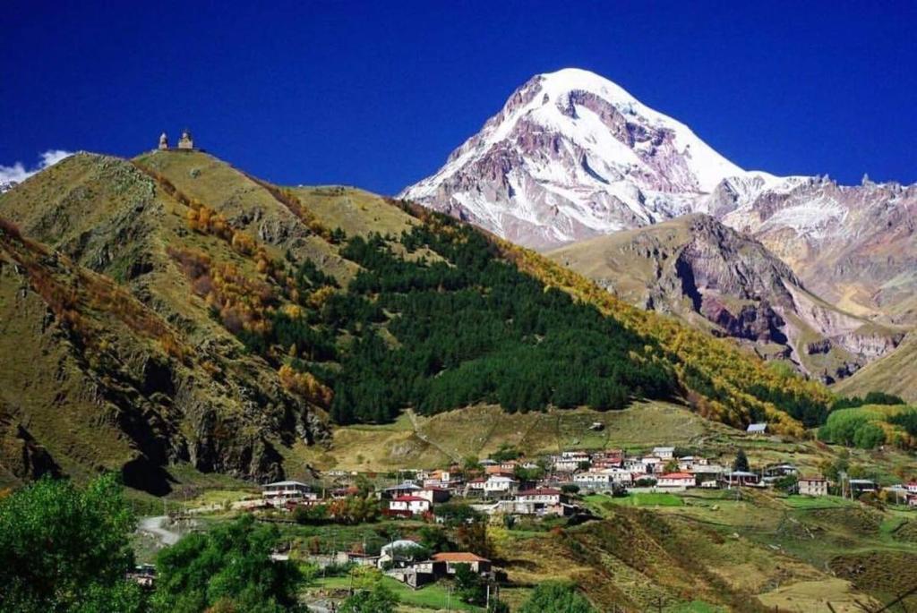 une montagne avec un village en face d'une montagne dans l'établissement Tamila Guest House, à Kazbegi