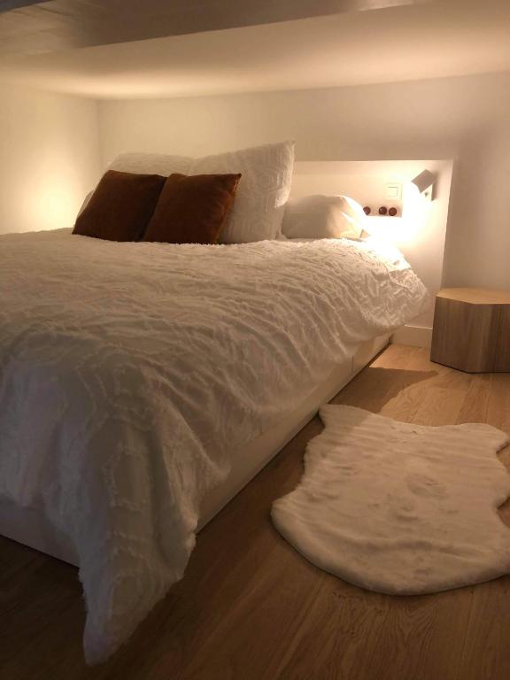 une chambre avec un grand lit avec des draps et des oreillers blancs dans l'établissement L'appartement d'Eva, à Honfleur
