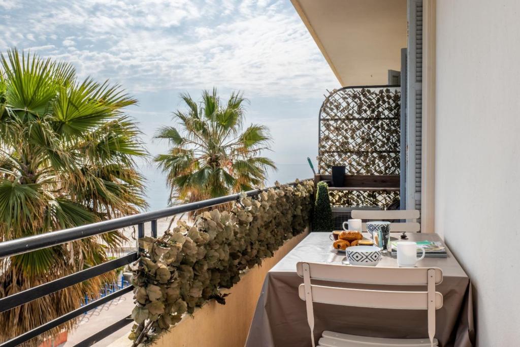 un balcon avec une table, des chaises et des palmiers dans l'établissement Apt With Balcony With Beach Vue, à Villeneuve-Loubet