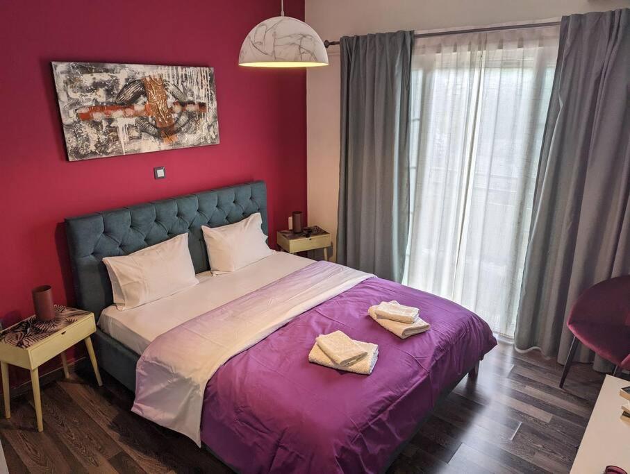 1 dormitorio con 1 cama morada y 2 toallas en Cozy apartm.near Metro Ag.Marina, en Atenas