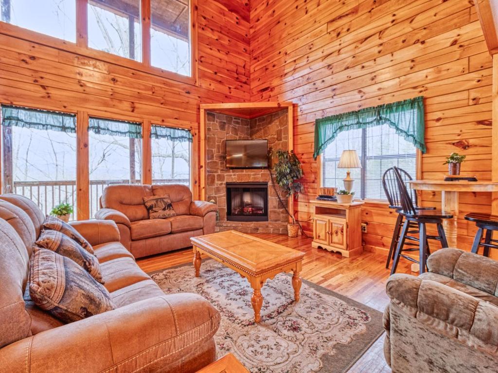 a living room with furniture and a fireplace in a log cabin at Hawks Point Lodge, 5 Bedrooms, Sleeps 10, Pool Access, Hot Tub, Pool Table in Sevierville