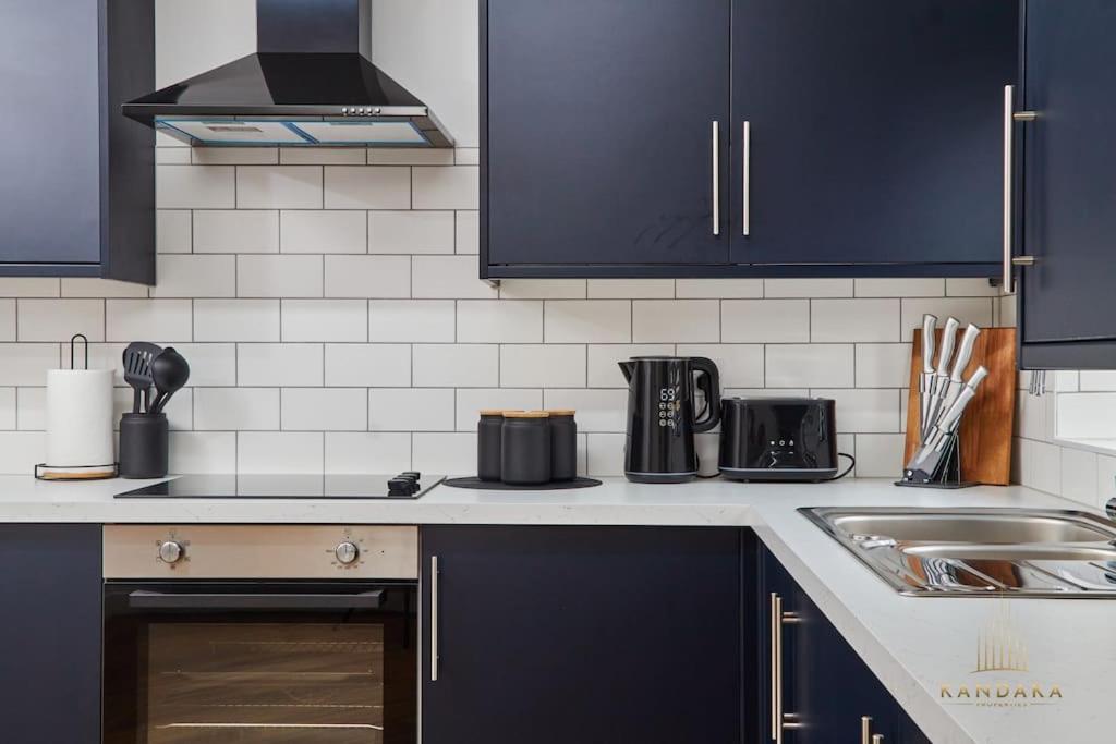 a kitchen with dark blue cabinets and a sink at Stunning 5Bed All En-suite Headingley Home in Headingley