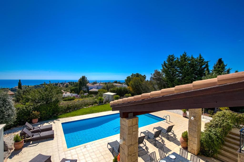 vista su una piscina con sedie e patio di Stunning 5 Bed Villa Calantha with Fantastic Outside Space - Aphrodite Hills a Kouklia