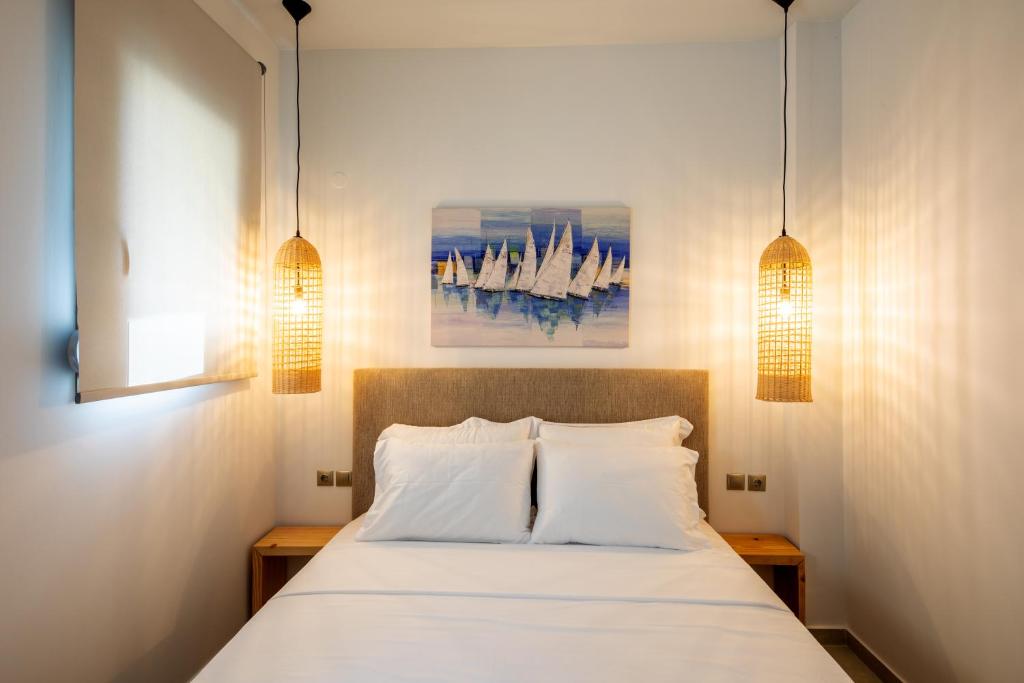 1 dormitorio con 1 cama blanca y 2 lámparas en portokoufovillas en Porto Koufo
