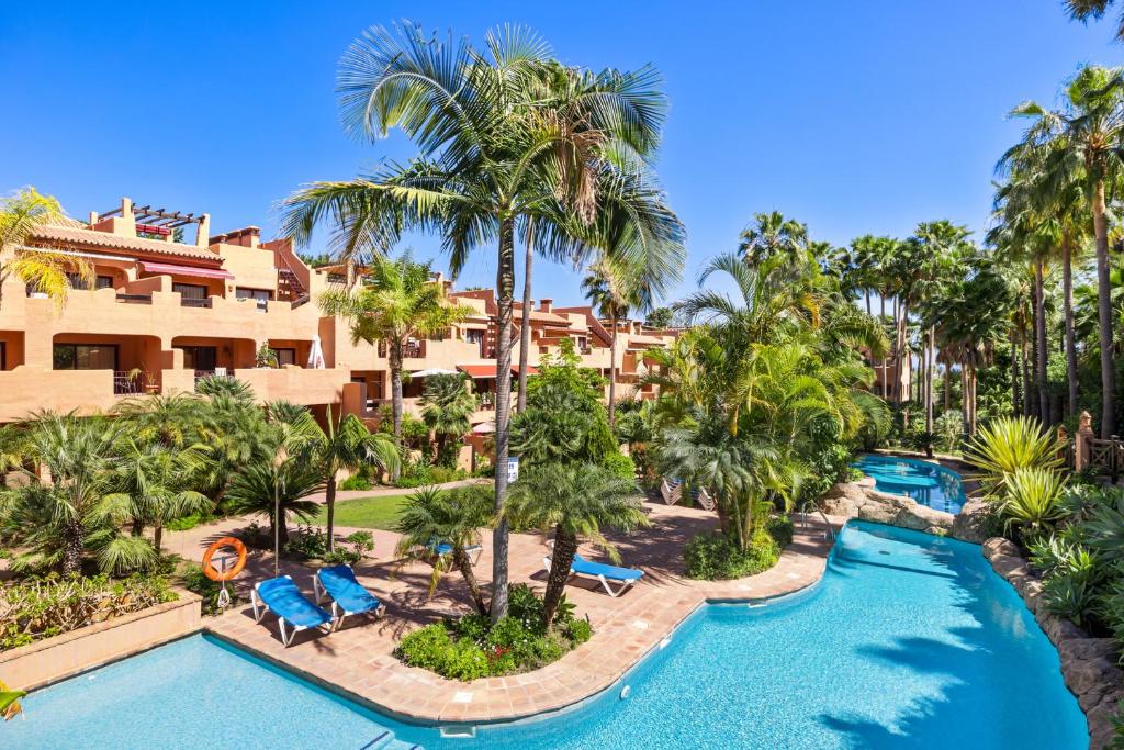 - une vue aérienne sur un complexe avec une piscine et des palmiers dans l'établissement Beautifull penthouse, BIG solarium with seaview and exotic oasis gardens, à Estepona