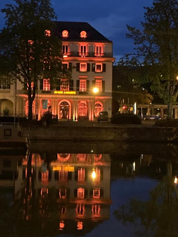 une grande maison avec des lumières rouges sur elle la nuit dans l'établissement King size lounge 76m2 de confort au centre ville, à Mulhouse