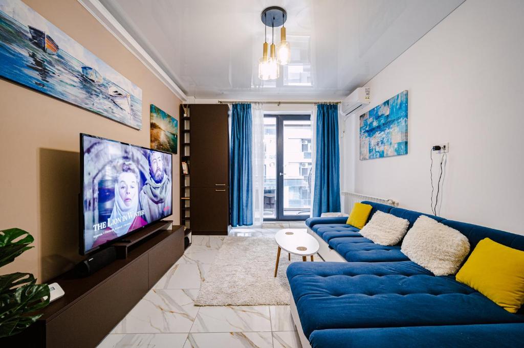 a living room with a blue couch and a tv at Seaside Blues Apartment Located in 5 Star Resort in Năvodari