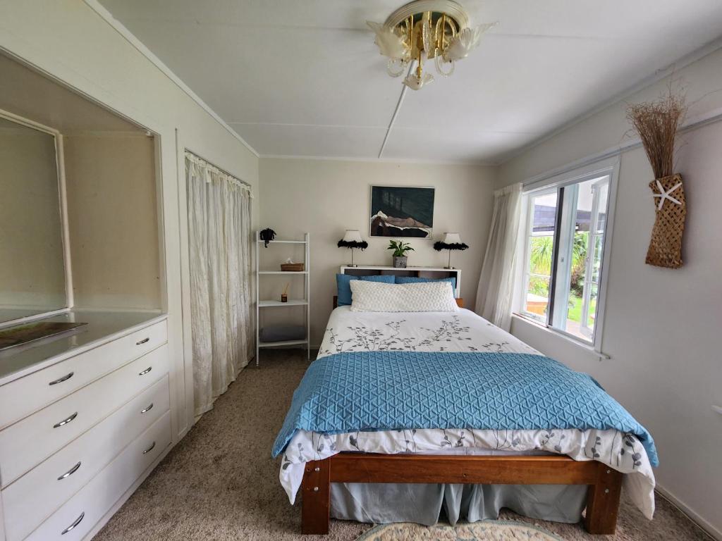 1 dormitorio con cama y lámpara de araña en La Petite Ferme Manor Kerikeri, en Kerikeri