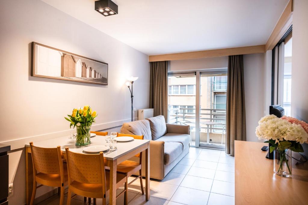 ein Wohnzimmer mit einem Tisch und einem Sofa in der Unterkunft Belcasa Suitehotel in Middelkerke