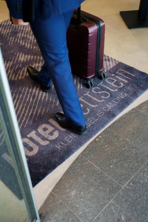 a person walking on a carpet with a suitcase at Hotel Wettstein in Basel
