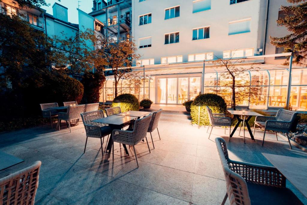 eine Terrasse mit Tischen und Stühlen und ein Gebäude in der Unterkunft Hotel Wettstein in Basel