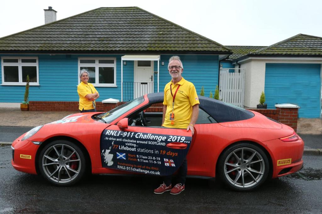 a man is standing next to a red car at Barr Hill Woods B&B in Kirkcudbright