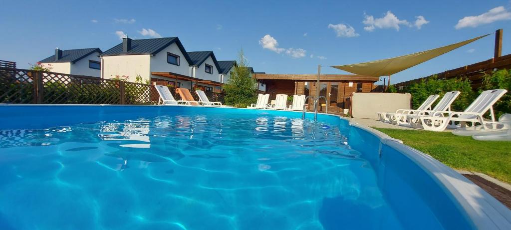 a swimming pool with white chairs in a yard at Corden Village in Łeba