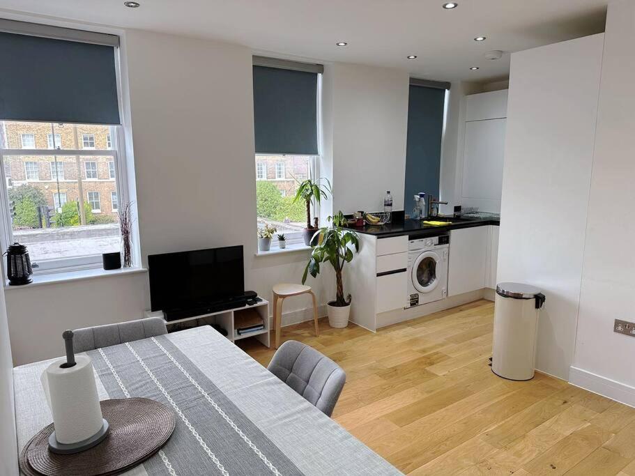 a living room with a table and a kitchen at Luxury Flat Near Greenwich Park in London