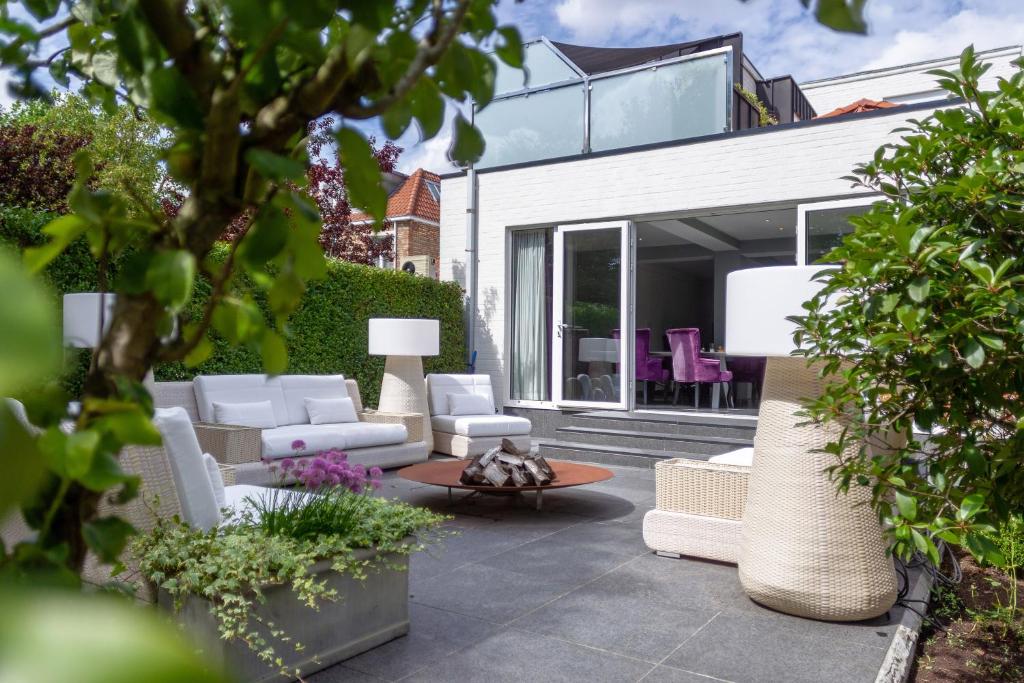 a patio with white furniture and a house at Saint Georges Bruges Luxury Suites in Bruges