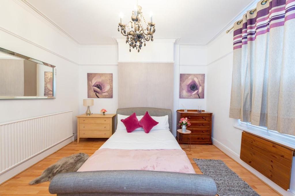 a bedroom with a bed with red pillows and a chandelier at Captivating 5-Bed House in Liverpool with parking in Liverpool