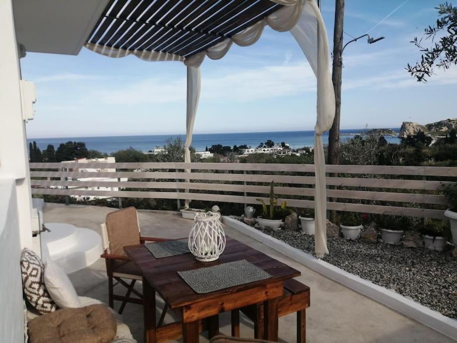 a table and chairs on a patio with a view of the ocean at Filia Bungalow in Archangelos