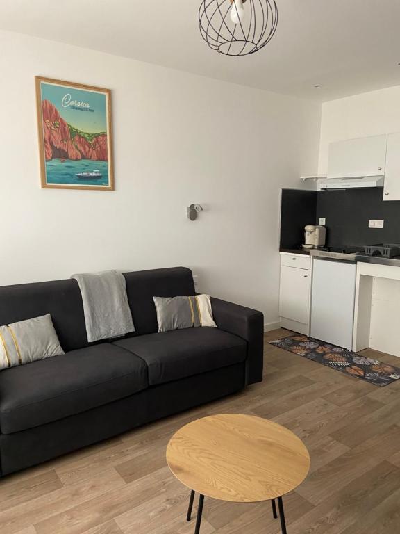 a living room with a black couch and a table at Résidence City Suites Ajaccio in Ajaccio