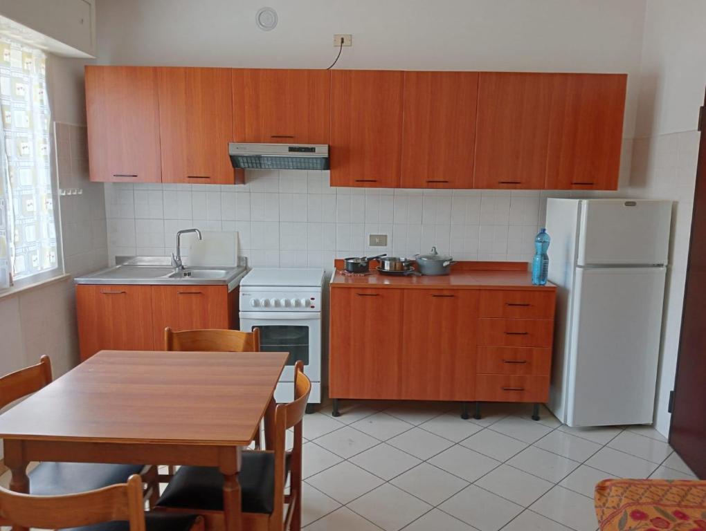 eine Küche mit einem Tisch und einem weißen Kühlschrank in der Unterkunft Appartamenti Carlotta in Rimini
