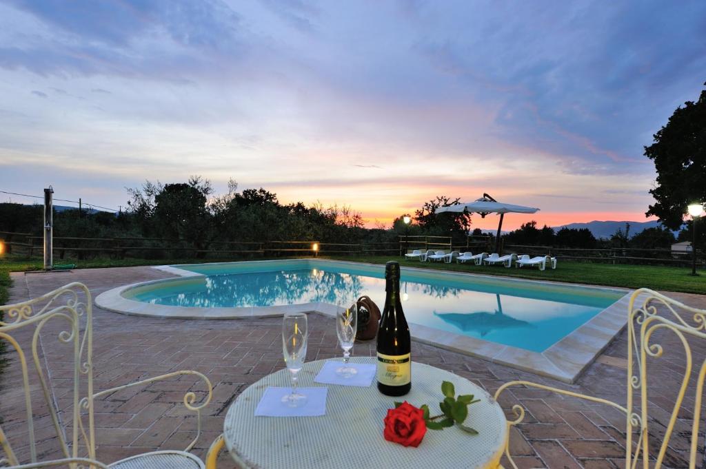 uma mesa com uma garrafa de vinho ao lado de uma piscina em Girasole - Agriturismo Fogliani em Giano dellʼUmbria