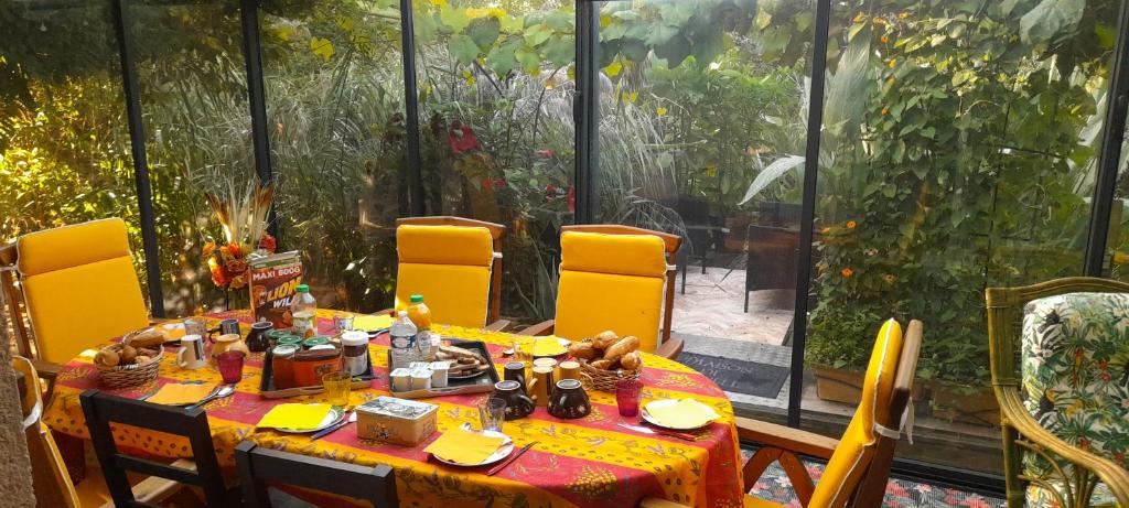 a table with yellow chairs around it in a greenhouse at chambres d'hôtes naturistes de la moque souris in Saint-Pierre-de-Mailloc