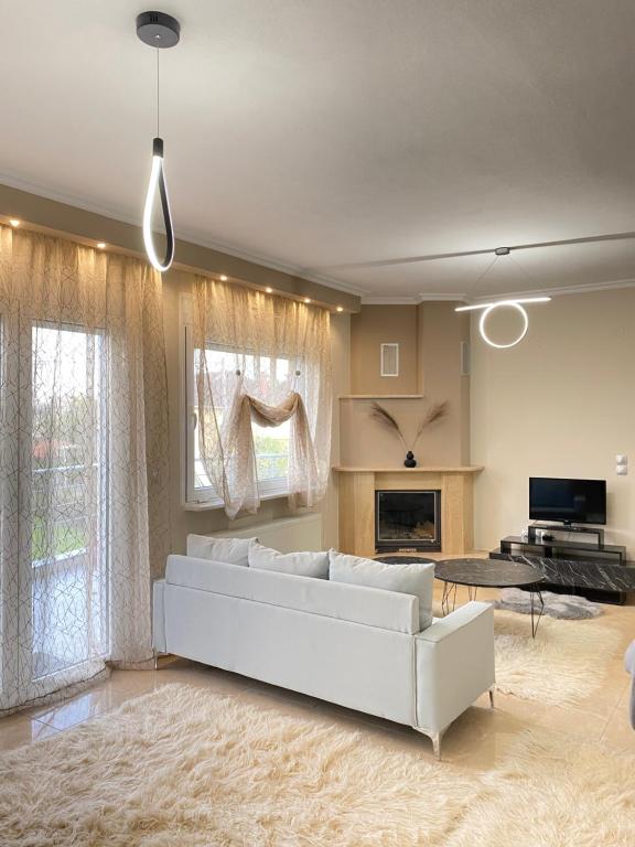 a living room with a white couch and a fireplace at Olymp Family Apartments Katerini in Katerini