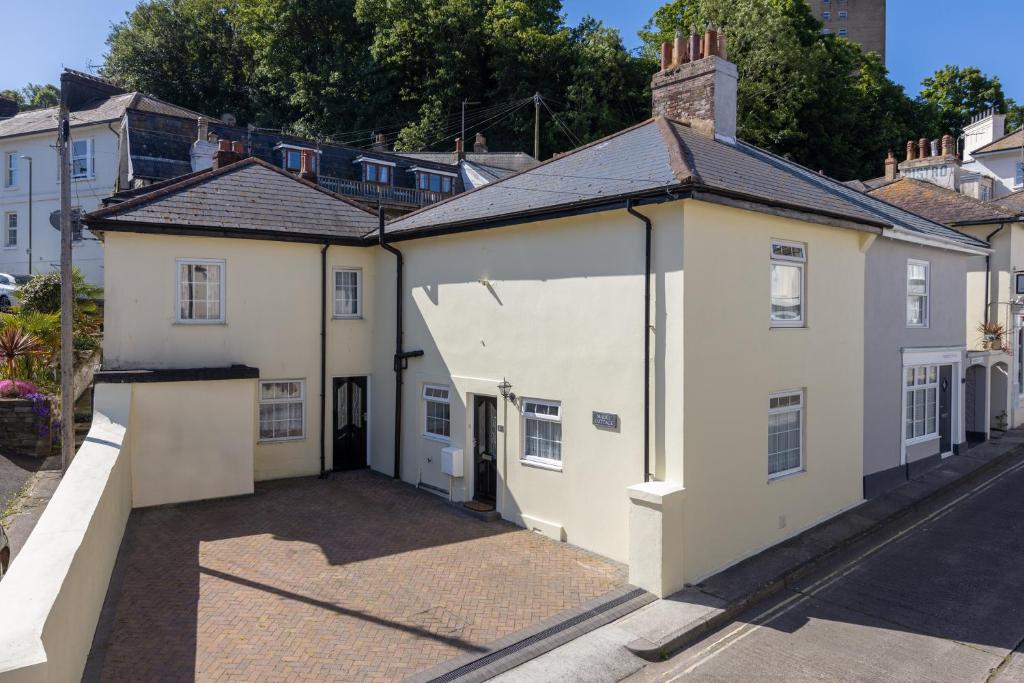 a large white house with a garage on a street at Mabel Cottage in Torquay
