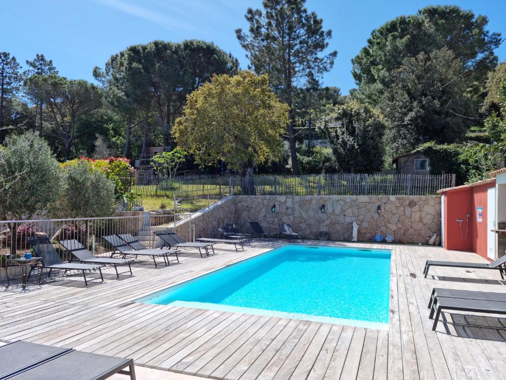 een zwembad in een tuin met stoelen en een hek bij Hôtel Casa di Mama in Porto-Vecchio