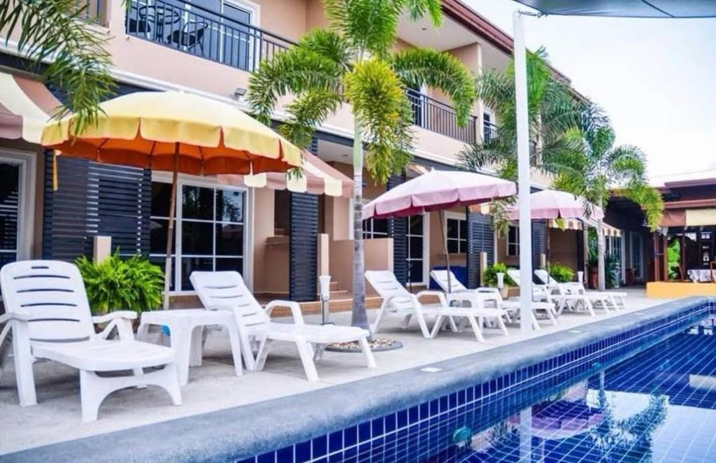 4 Palms Resort في بانغ ساري: مجموعة كراسي ومظلات بجانب مسبح