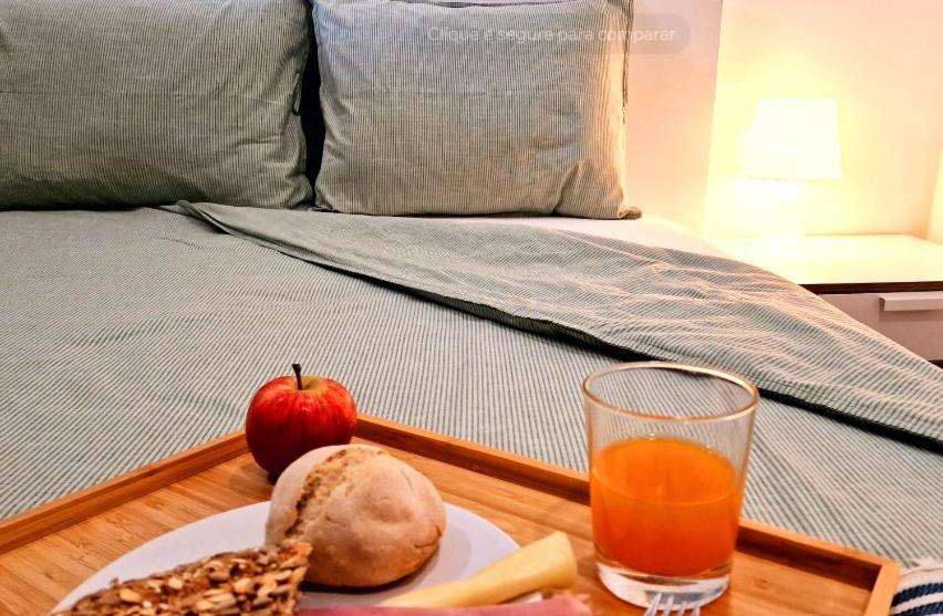 a plate of fruit and a glass of orange juice on a bed at Casa Vila Praia in Sesimbra