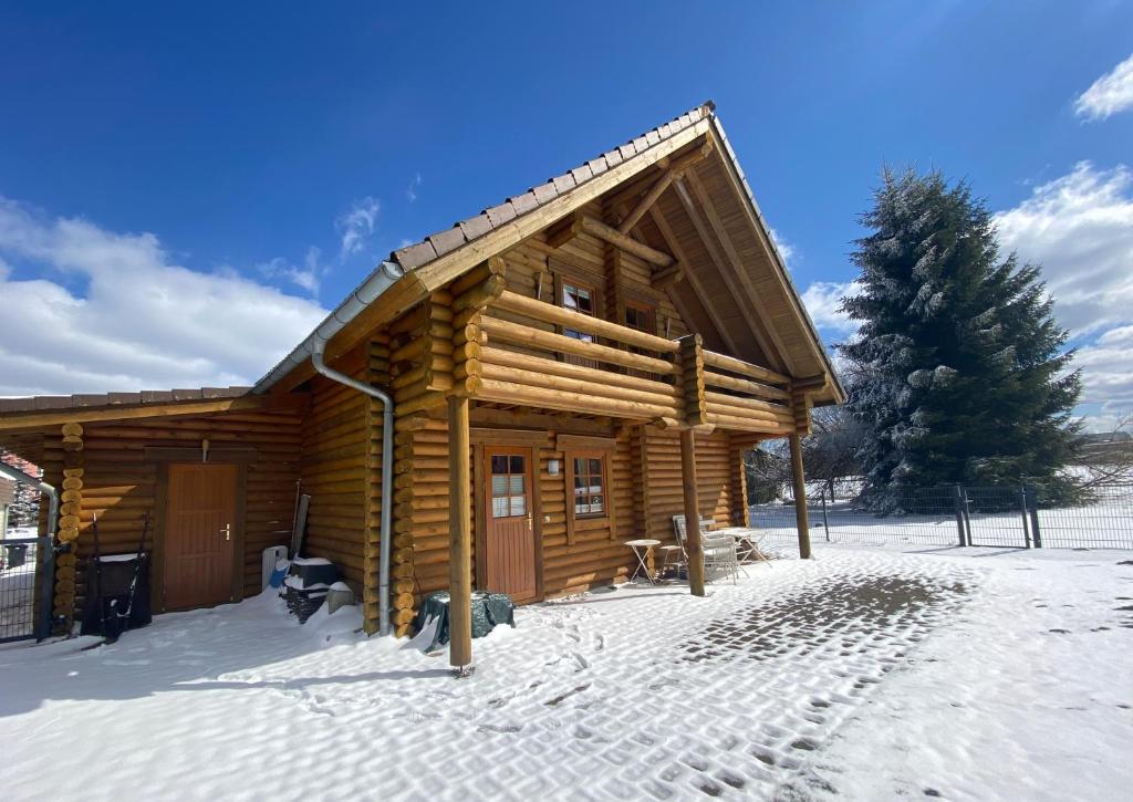 Cabaña de madera con nieve en el suelo en Blockhaus Rennsteig, en Neuhaus am Rennweg