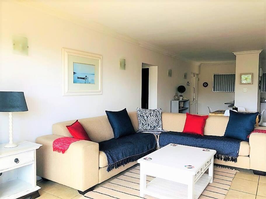 a living room with a couch with red and blue pillows at Aquarella 1 in Plettenberg Bay