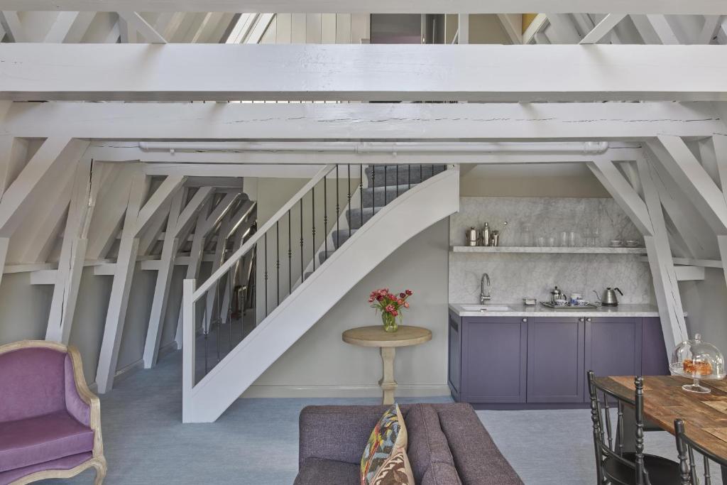 a room with a staircase with a table and a couch at Pulitzer Amsterdam in Amsterdam