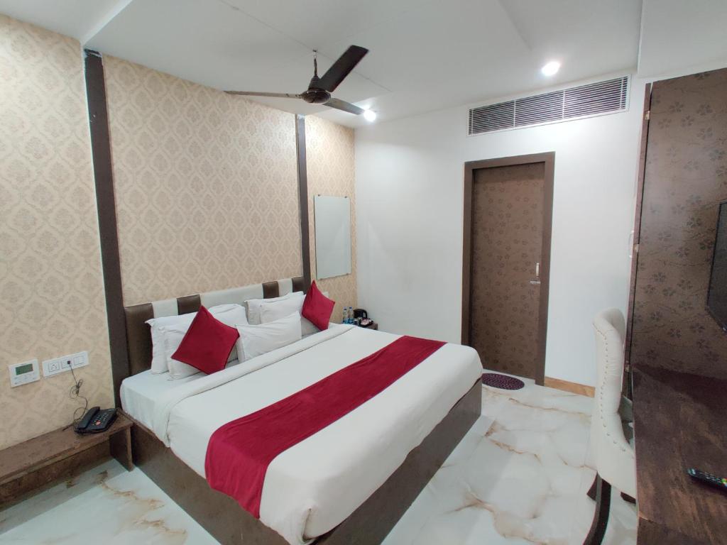 a bedroom with a large white bed with red pillows at Hotel Tamanna - 50 Meter from Golden Temple in Amritsar