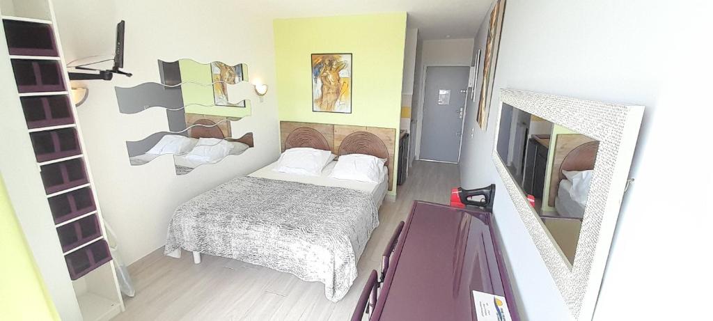 um pequeno quarto com uma cama e um espelho em Studio Village Naturiste Lollipop em Cap d'Agde