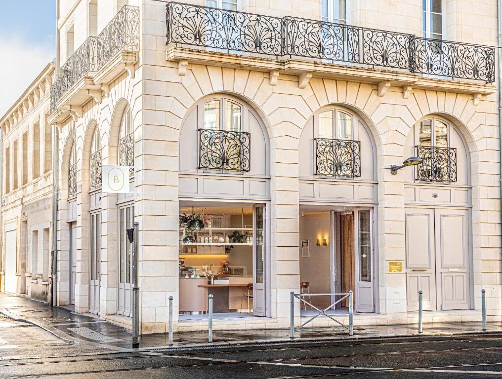 biały budynek z balkonem przy ulicy w obiekcie La Maison De Blanche w mieście Bordeaux