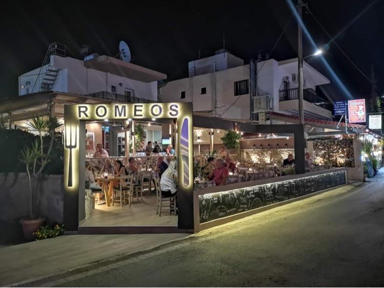 a restaurant with a sign that reads romanos at night at Romeos Studios in Agia Marina Nea Kydonias