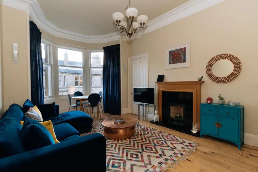 a living room with a blue couch and a fireplace at Beautiful Home In Stockbridge Edinburgh in Edinburgh