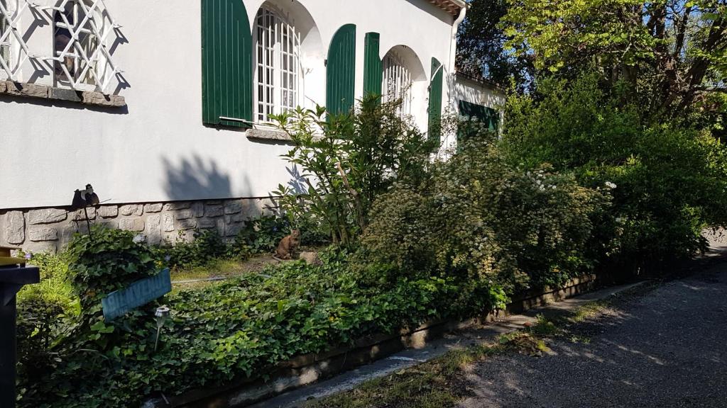 un bâtiment avec des fenêtres et des buissons verts à volets dans l'établissement Villa CAMBOUNET, Maison cosy à quelques kilomètres des plages, à Béziers